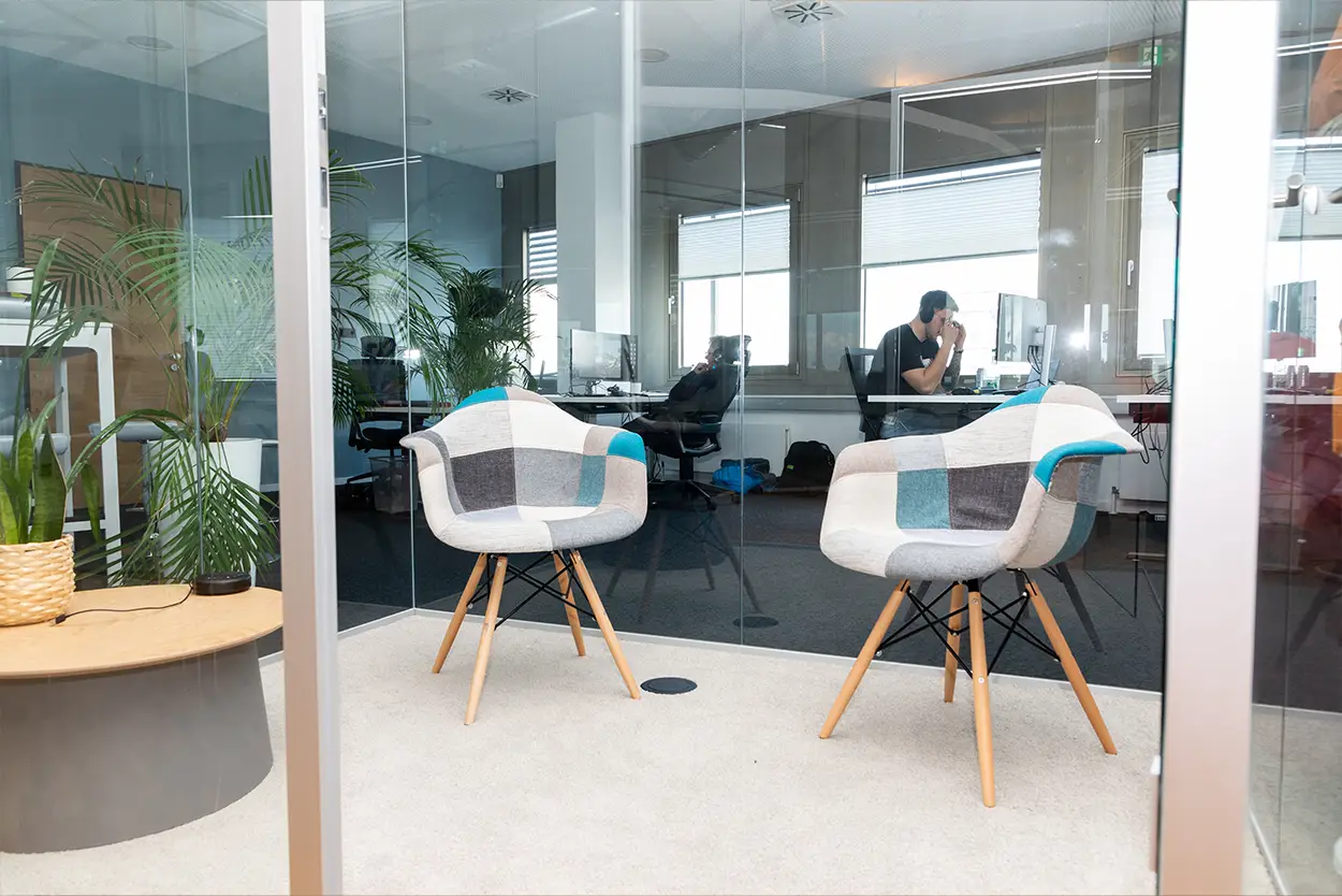 Zwei bequeme Sessel im Break-Out-Room dem Zimmer eines verglasten Großraumbüros